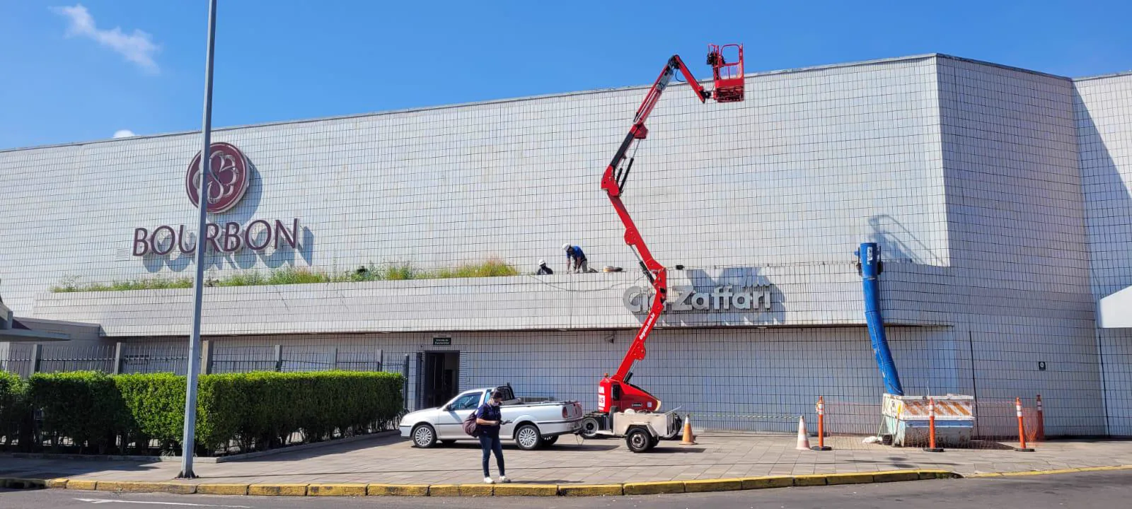 Equipe da Shop Engenharia revitalizando a fachada de um centro de compras, com plataforma articulada.